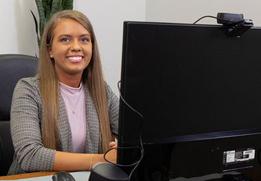Person smiling next to computer